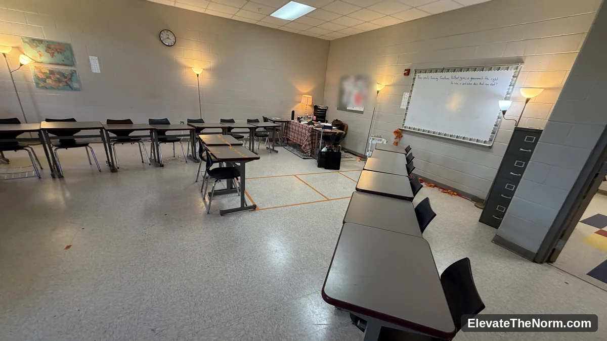 The same secondary classroom with the overhead fluorescent lights switched on, producing flat even light across the desks and floor